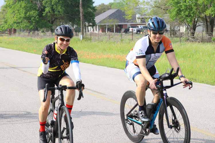Brightly colored cyclists enjoying a ride on a scenic rural road during daytime.
