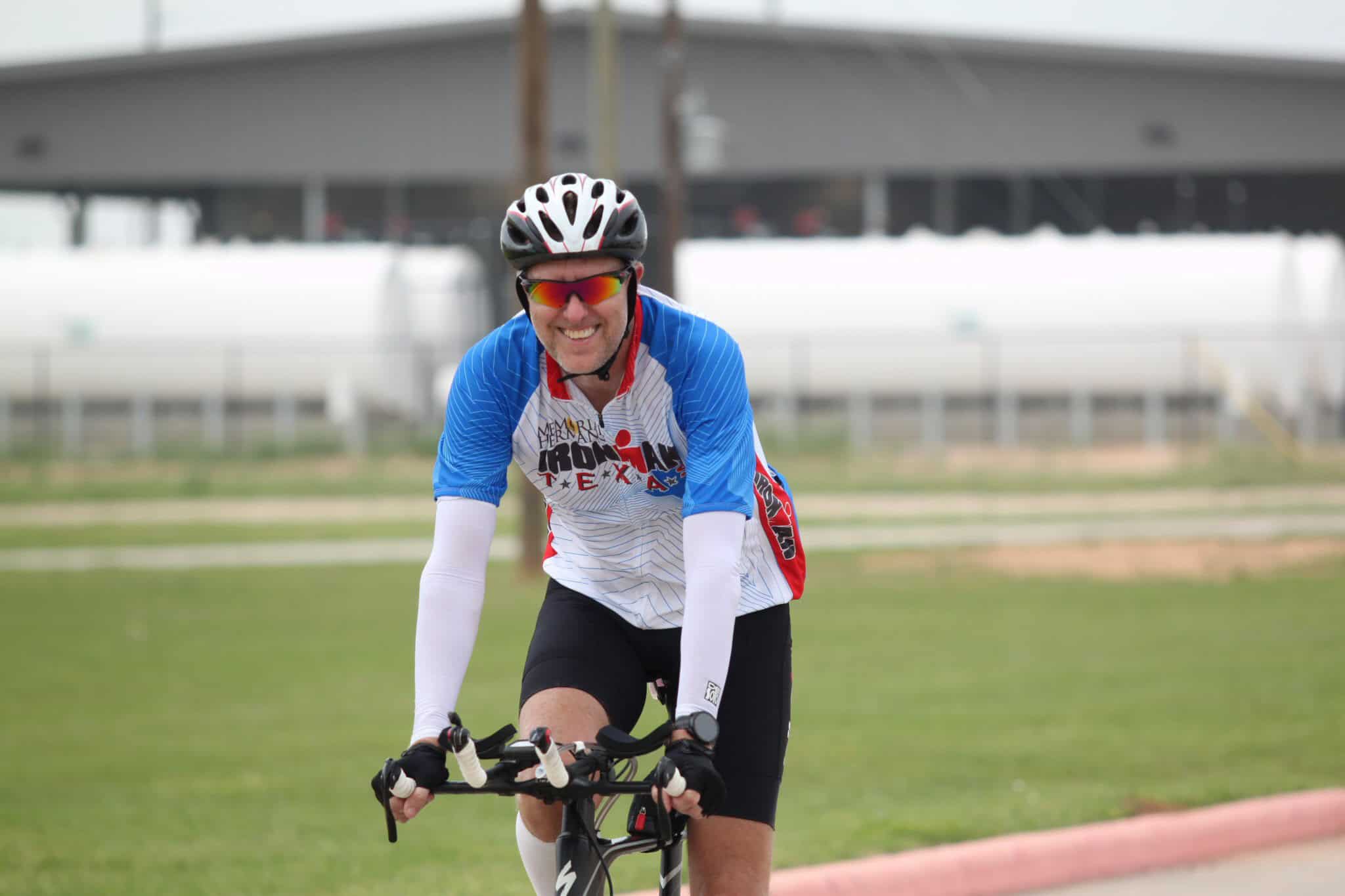 Active cyclist riding a bike, smiling with a blue and white jersey, celebrating Bluebonnet Express race.