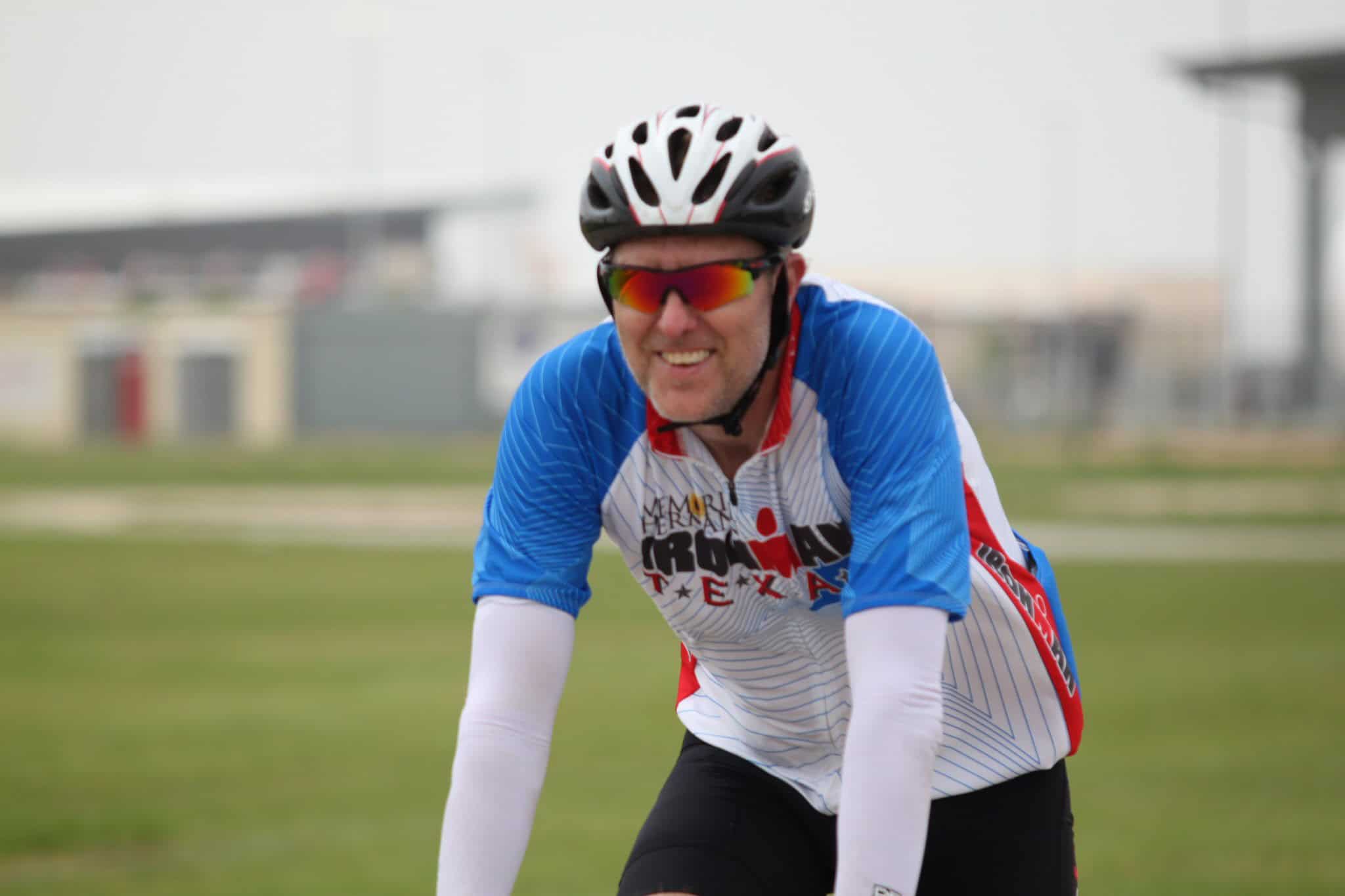 High-performance cyclist wearing blue and white jersey, black helmet, and sunglasses during a race.