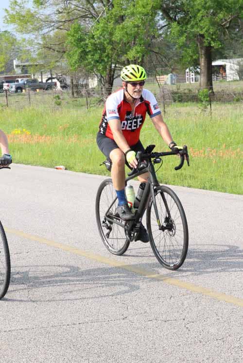 Bright yellow helmet and cycling gear on male cyclist riding on rural road.