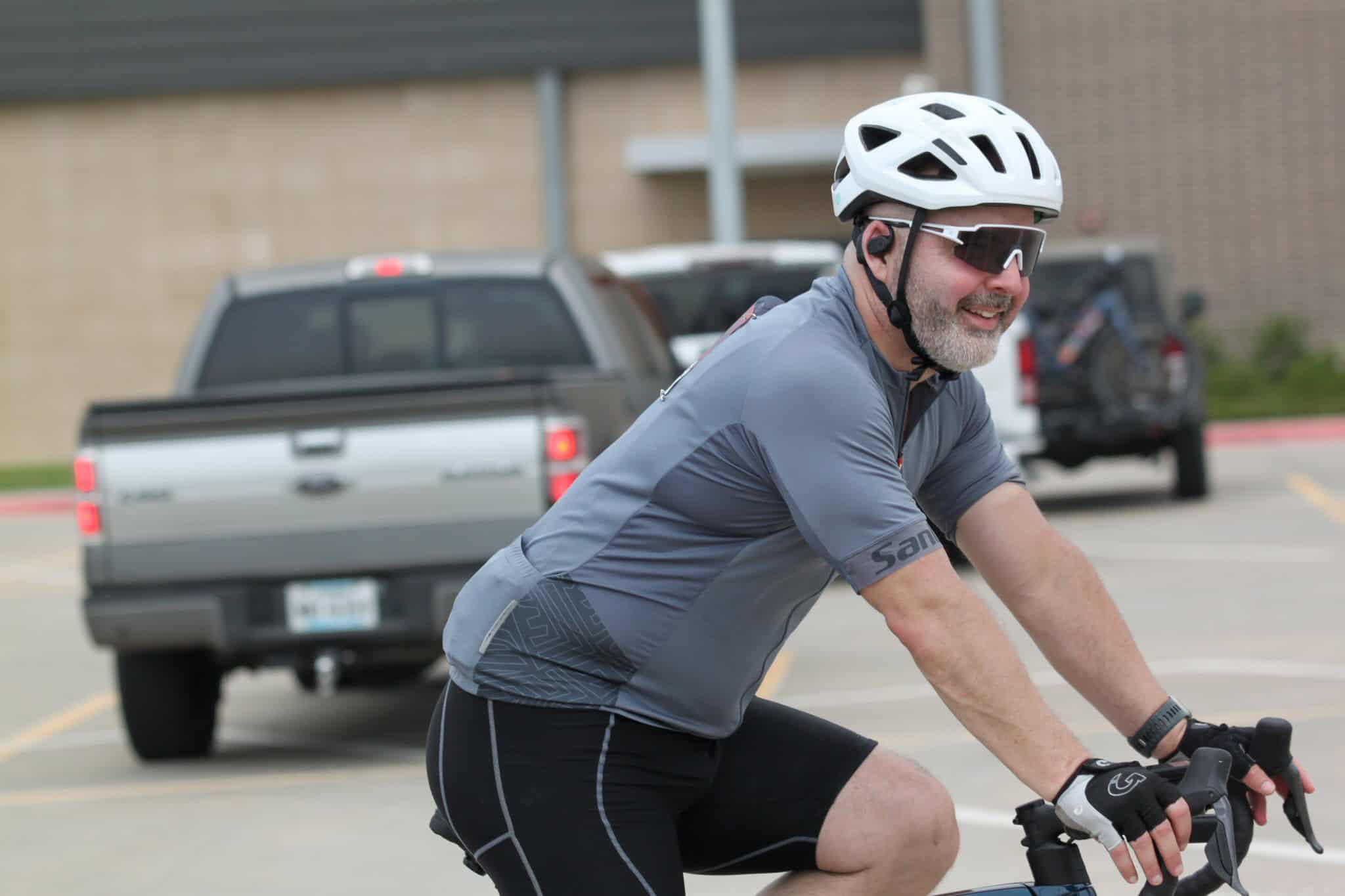 Pastel blue bicycle helmet with visor and sunglasses, male cyclist smiling, riding bike outdoors.