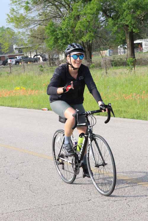 Smiling cyclist riding a road bike on a scenic outdoor trail in spring.