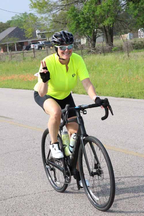 Bright yellow cycling jersey woman riding a bike outdoors during daytime.