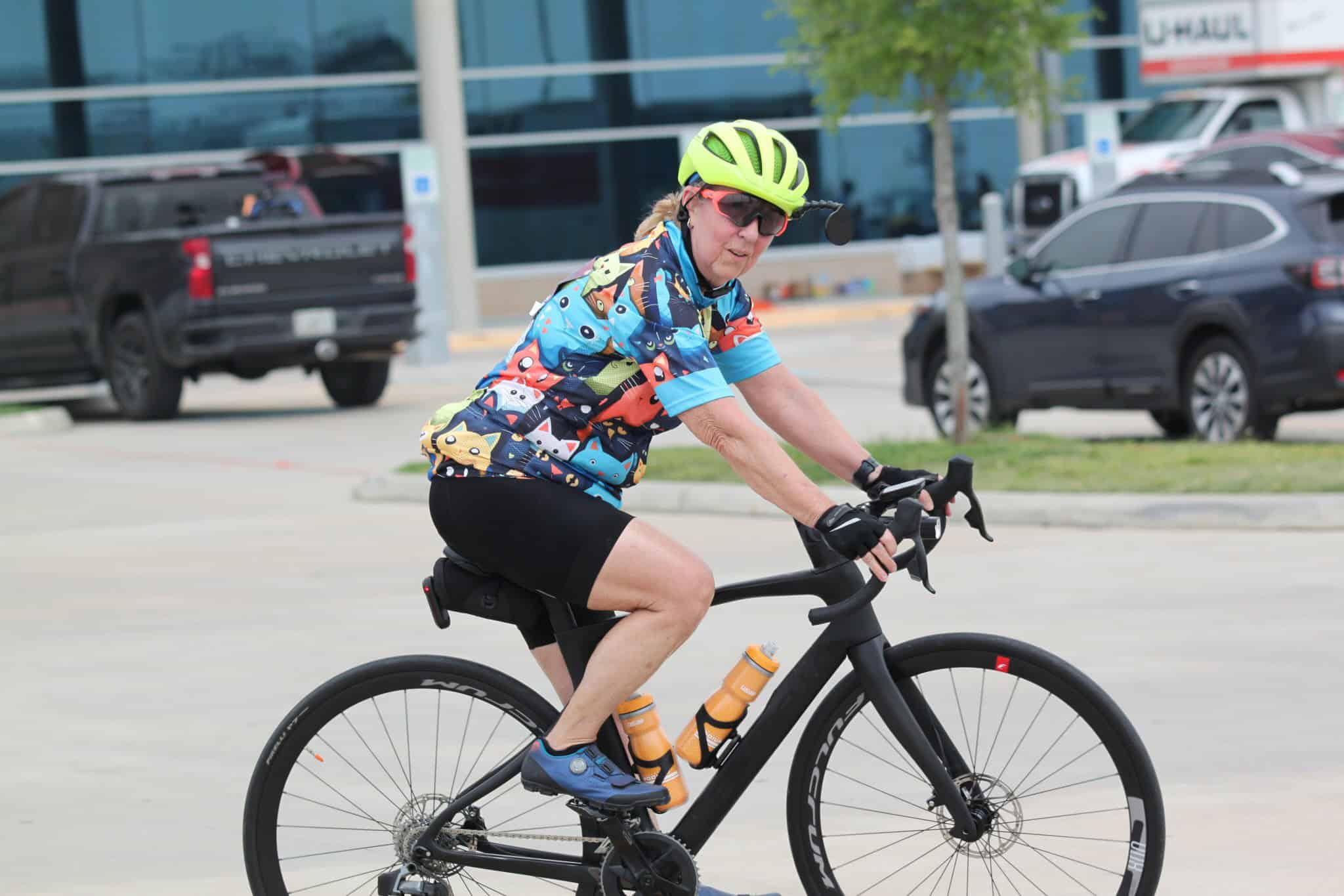 Bright green helmet and colorful cycling jersey on senior woman riding an e-bike.