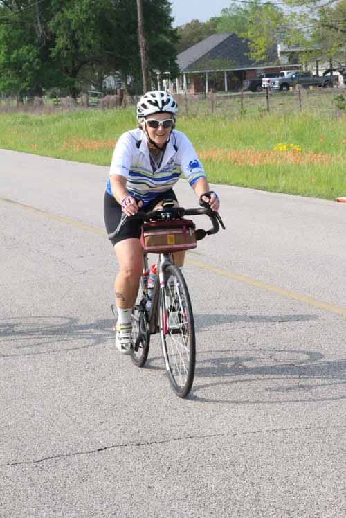 Bright woman cycling on a road with helmet and sunglasses for safety and outdoor exercise.
