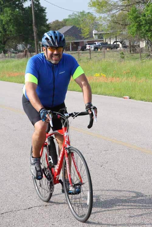 Vibrant cyclist riding a road bike during Bluebonnet Express event in scenic outdoor setting.