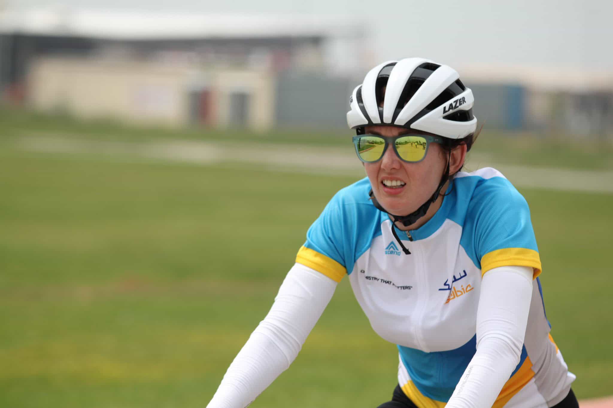 Velo cyclist wearing helmet and sunglasses riding on grassy track at Bluebonnet Express event.