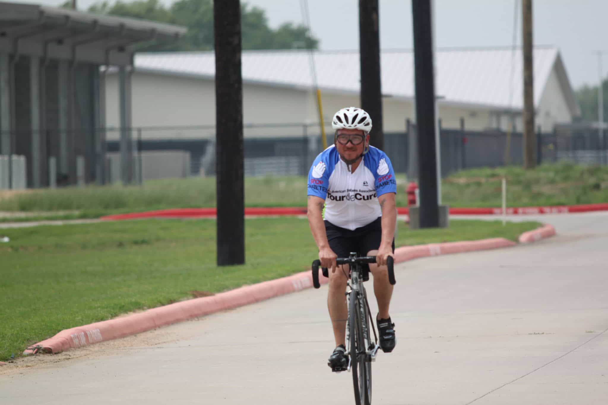 Efficient cyclist riding on a paved path during daytime.