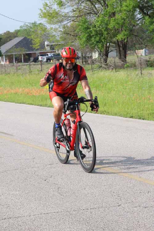Vibrant cyclist riding a red bike on a sunny outdoor road, enjoying a lively bike ride during daytime.