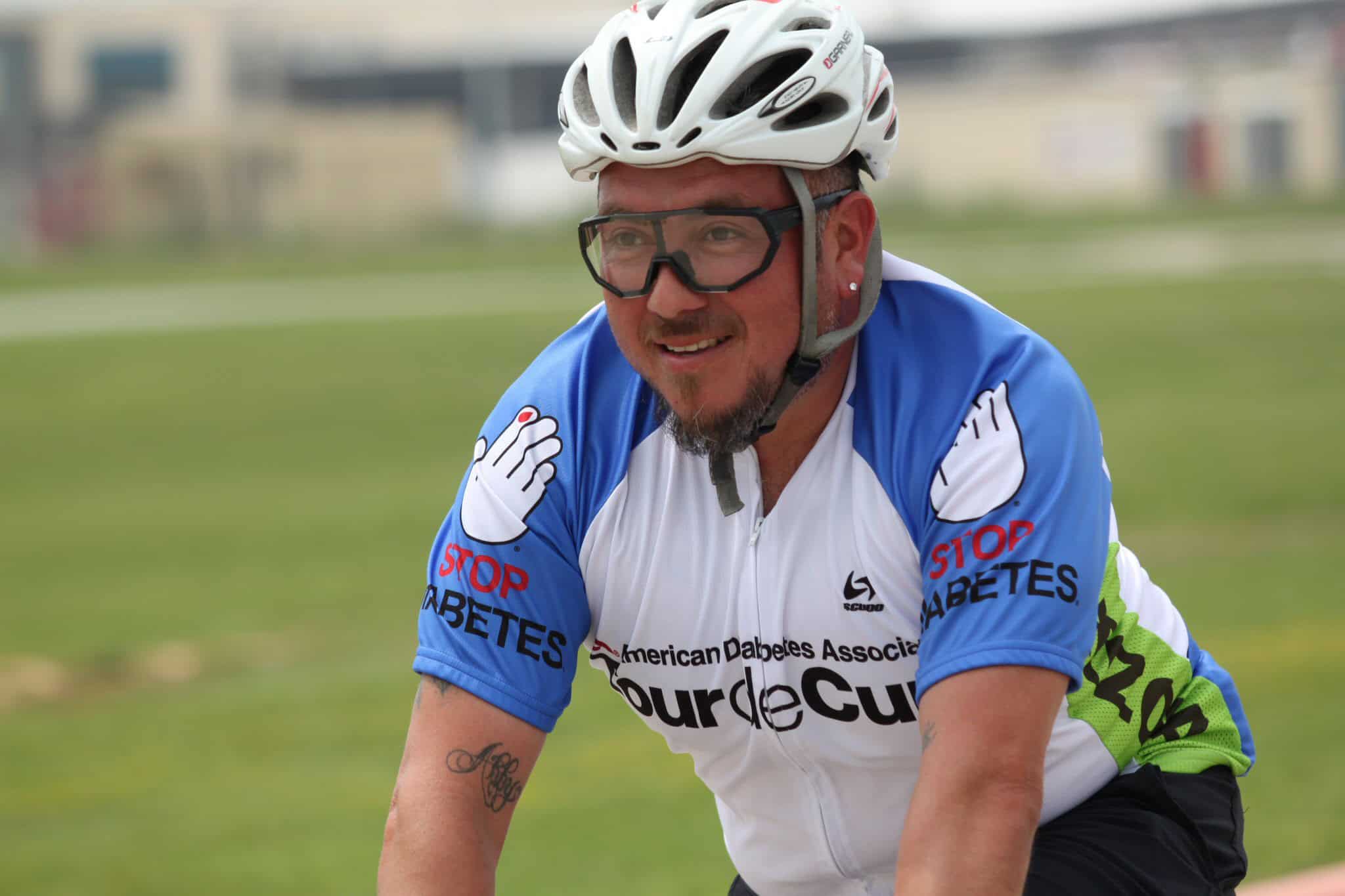 Bright male cyclist wearing a blue and white jersey with diabetes awareness message during outdoor ride.