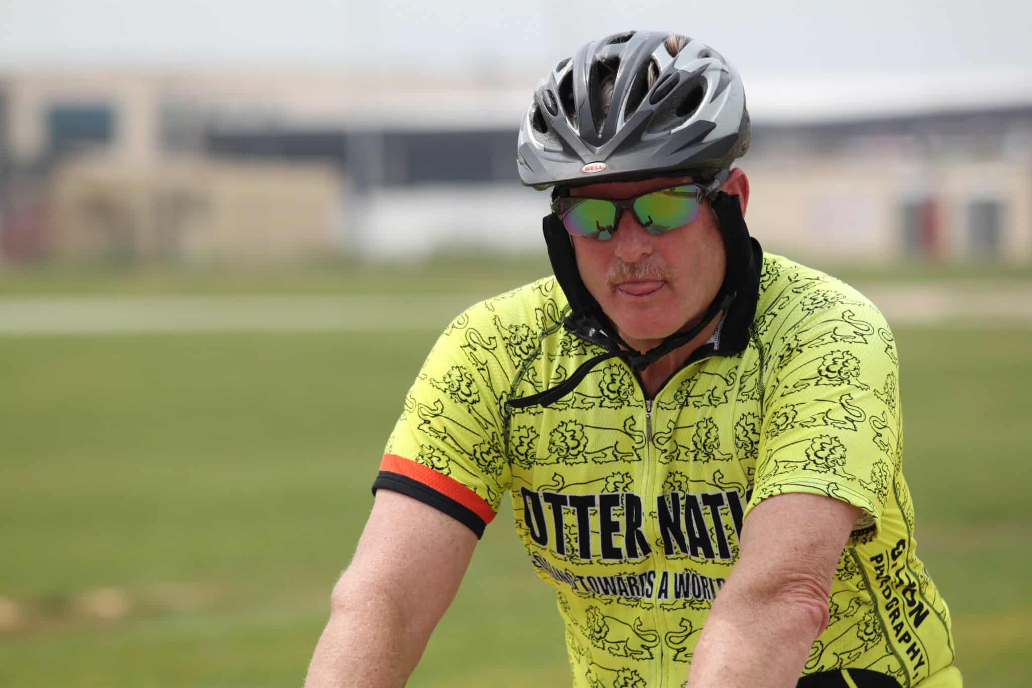 Cyclist in yellow Jersey and helmet riding bike on grassy field for Bluebonnet Express event.