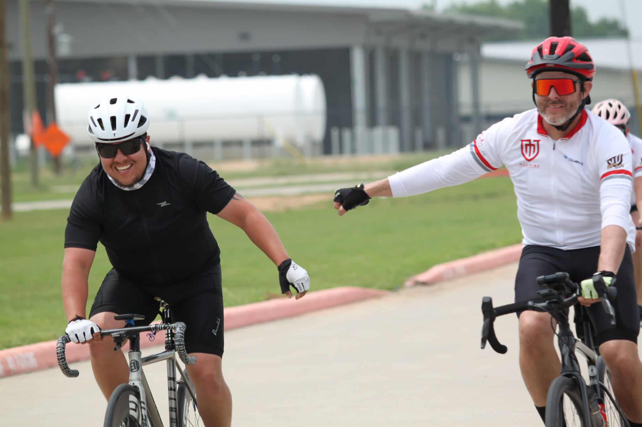 Smiling cyclists enjoying a ride with a friendly high-five on a scenic bike path.