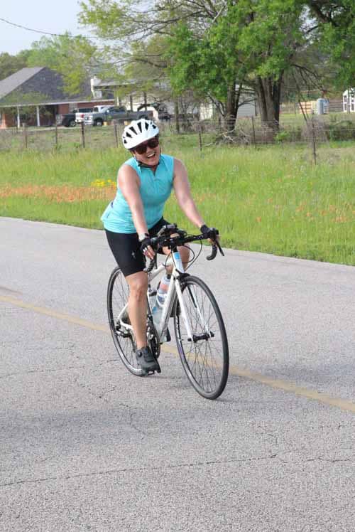 Bright woman enjoying cycling on a scenic bike route in a rural neighborhood.