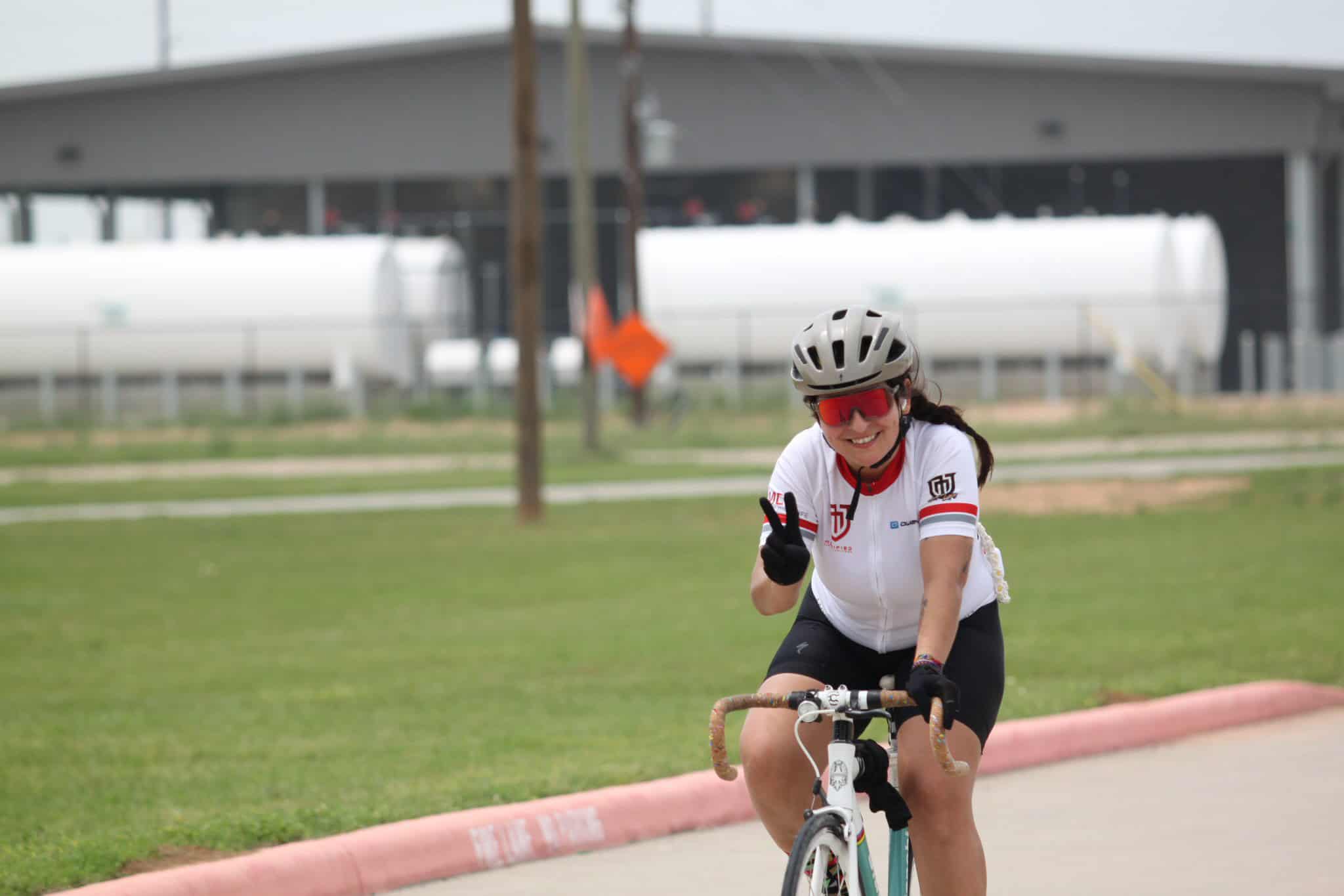 Vibrant cyclist smiling and making a peace sign during Bluebonnet Express ride event.