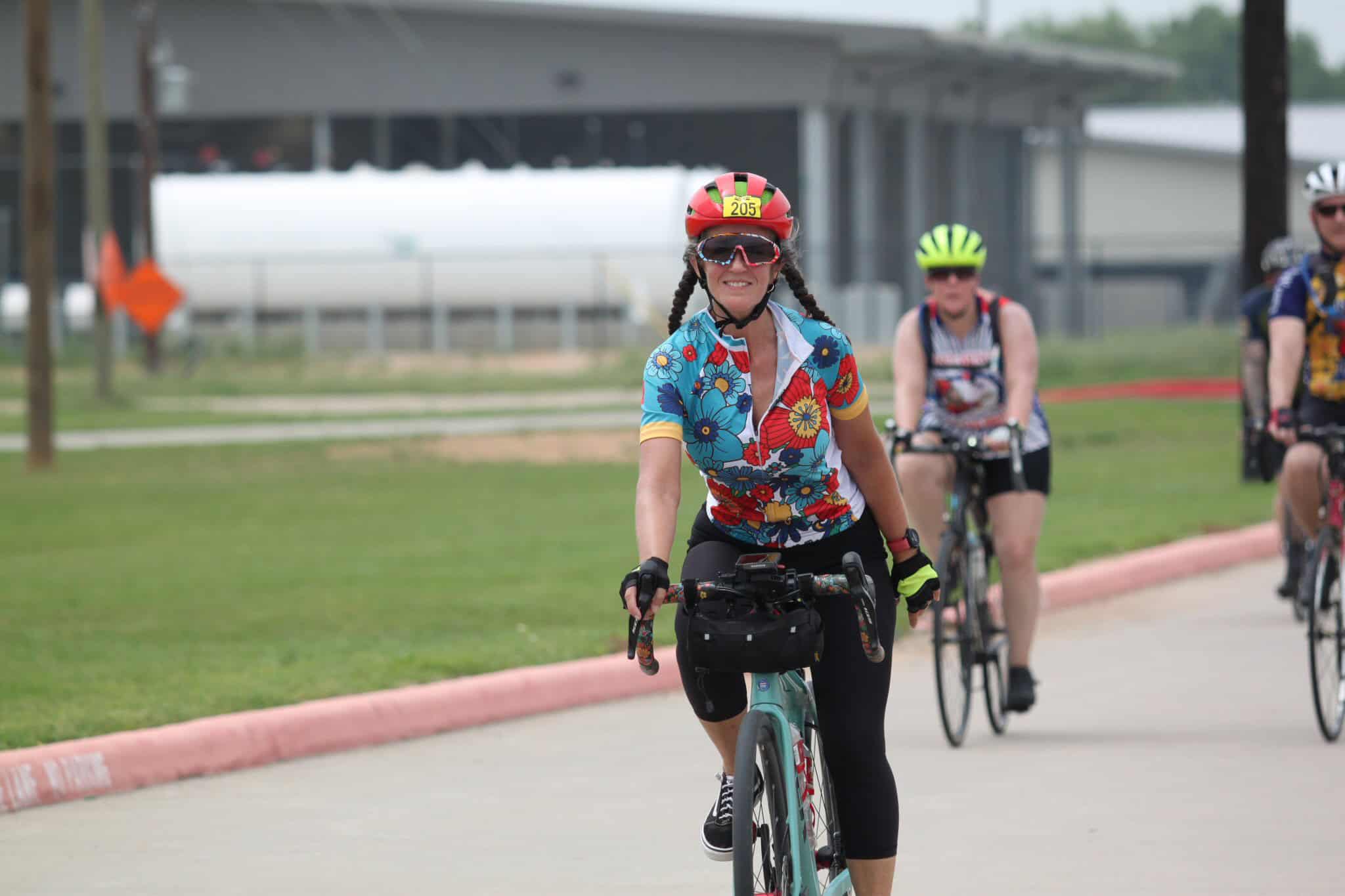 Bright woman cyclist riding during Bluebonnet Express event, smiling and enjoying the ride.