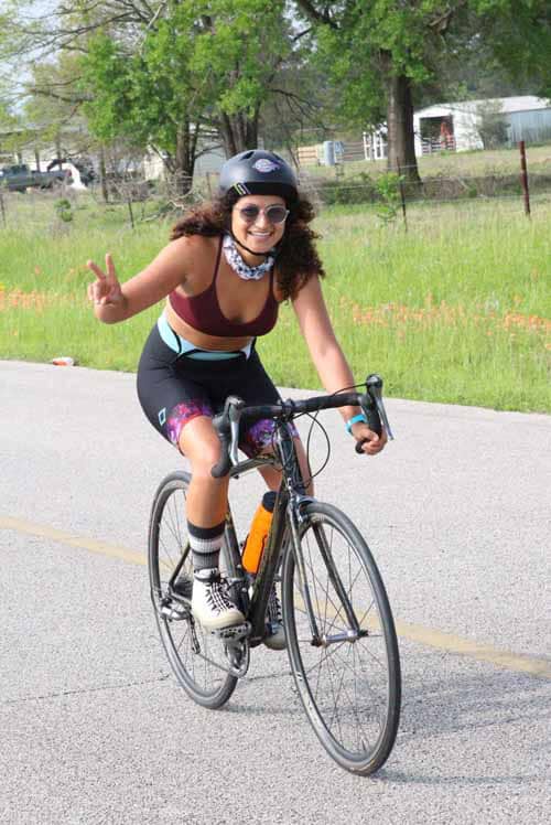 Victorious woman cyclist enjoying Bluebonnet Express ride outdoors.