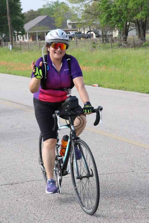Bright woman cyclist enjoying Bluebonnet Express ride on a sunny day, promoting outdoor adventure and fitness.