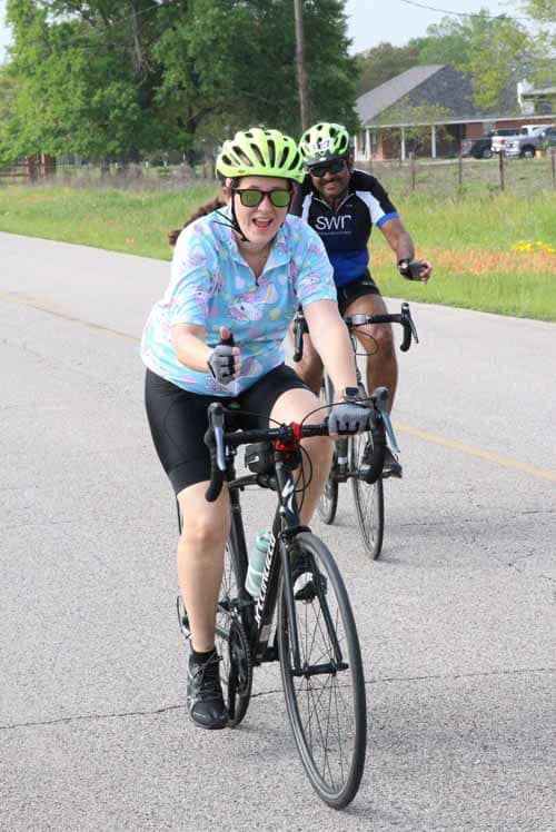 Bright female cyclist enjoying Bluebonnet Express bike tour on scenic Texas road.