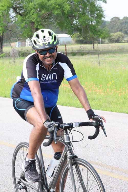 Energetic cyclist riding a road bike outdoors in green countryside.