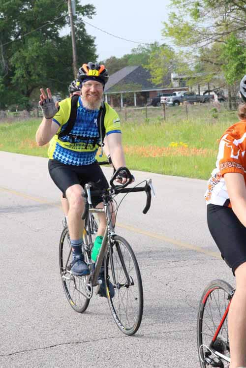 Smiling cyclist with a beard making peace sign during Bluebonnet Express bike ride event.