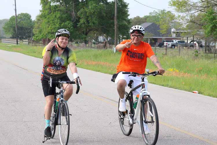 Two cyclists riding on a rural road, enjoying outdoor biking in nature.