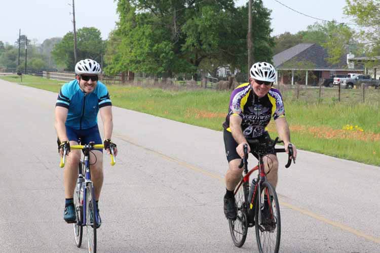 1. Two cyclists enjoying a ride on a countryside road with lush greenery.