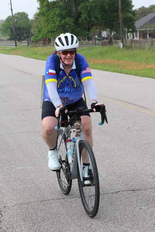 Bright senior cyclist riding a bike in Bluebonnet Express cycling event on rural road.