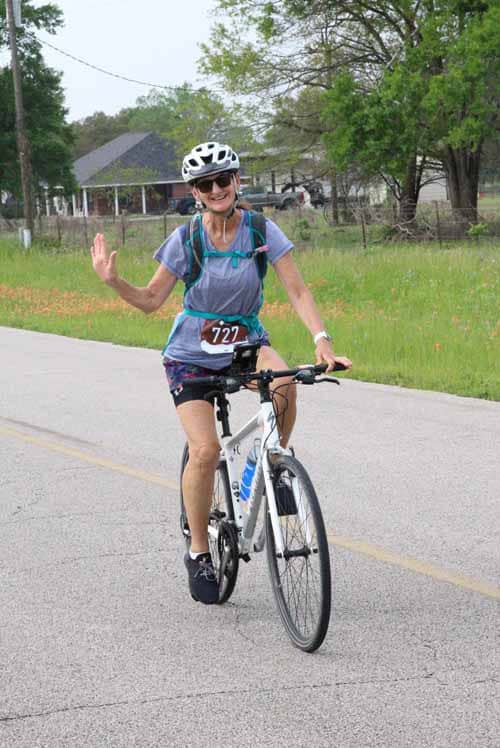Bright smiling woman cycling on road during Bluebonnet Express event, enjoying outdoor bike ride.