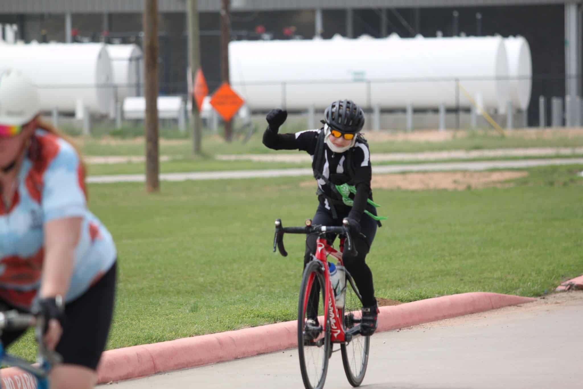 Bright cyclist celebrating victory after race finish on Bluebonnet Express route.