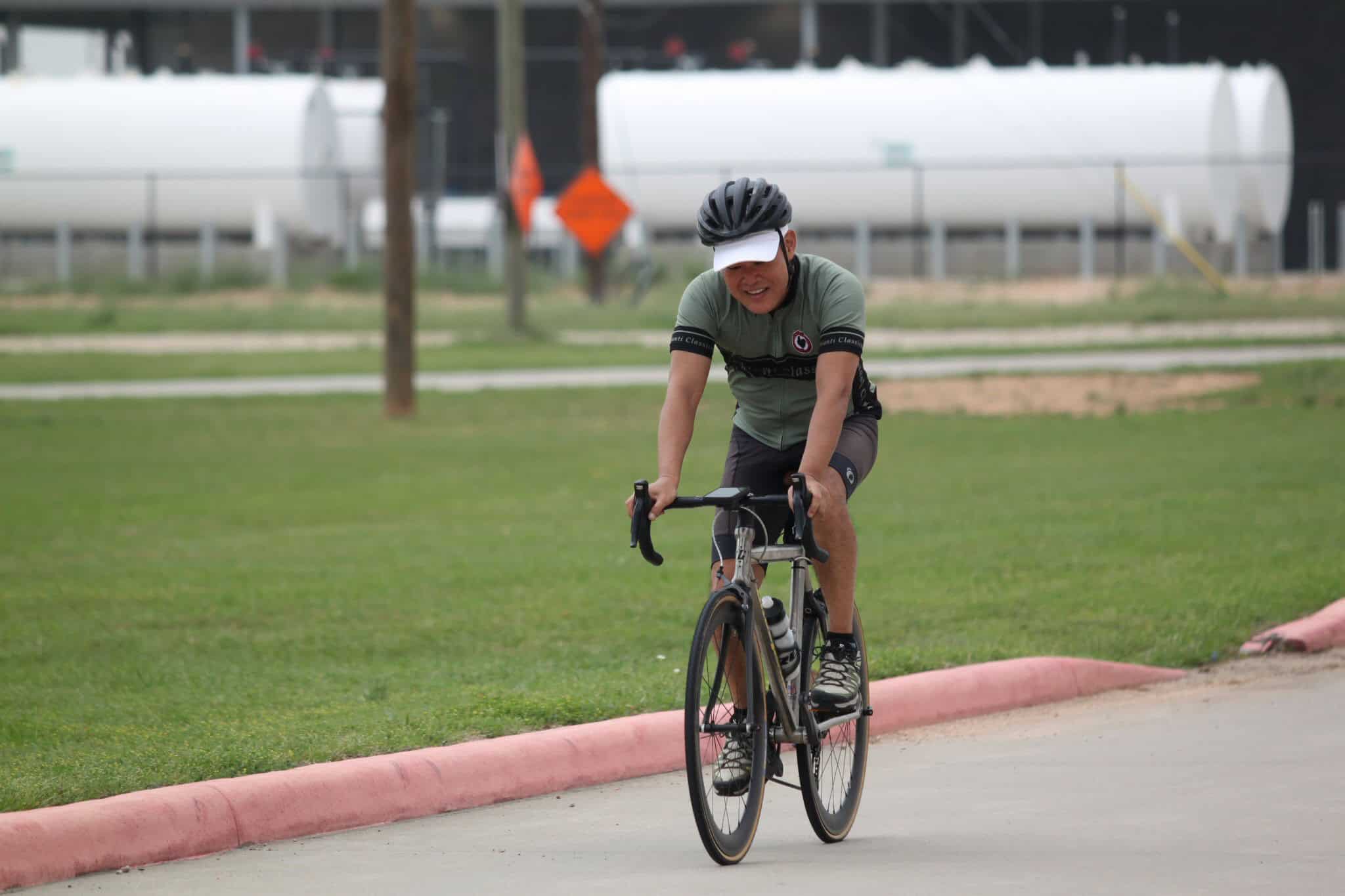 Enjoying a ride on the Bluebonnet Express bike trail, cyclist in helmet and sportswear, scenic outdoor weather, promoting active transportation.