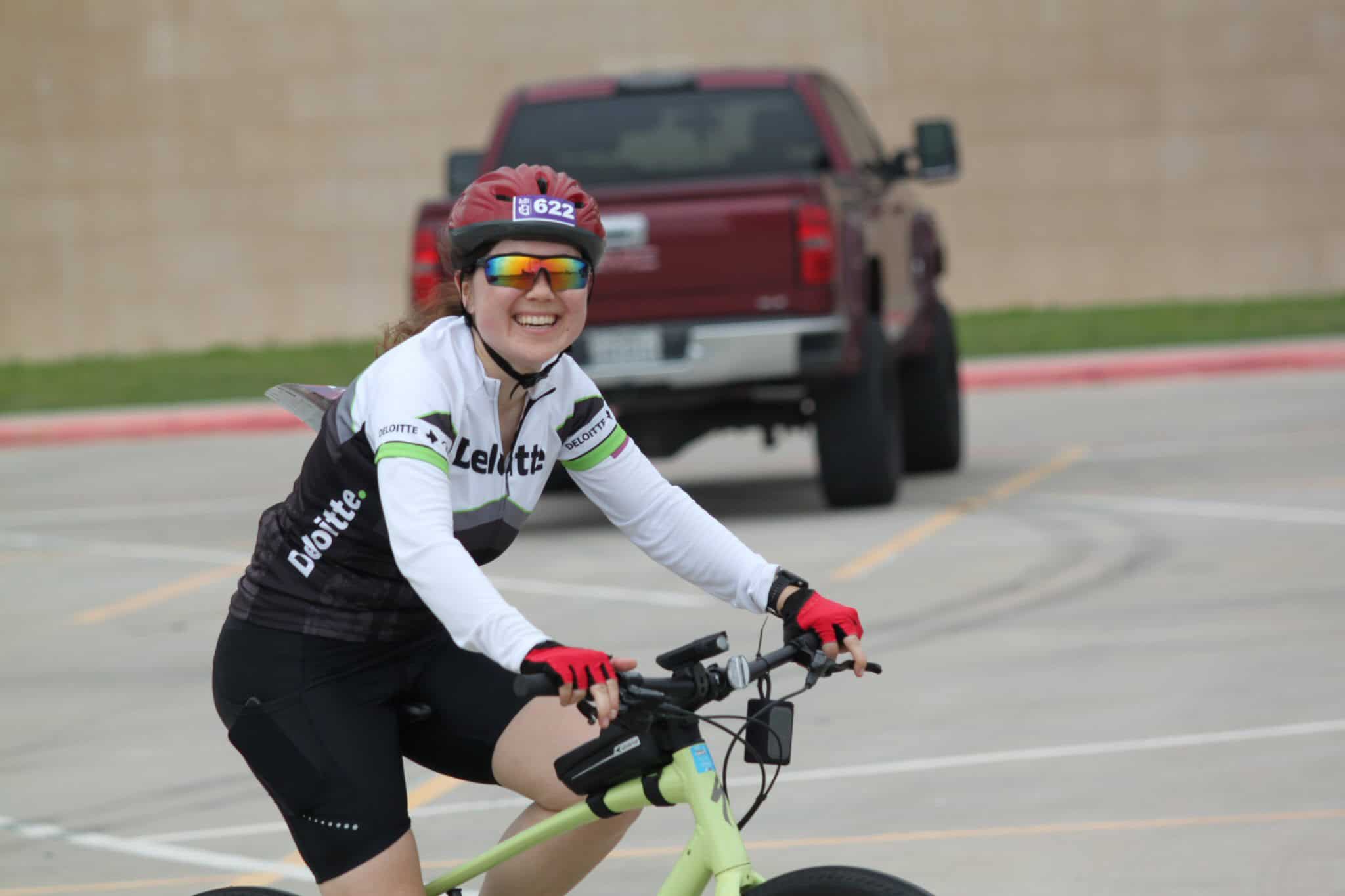 Smiling woman in cycling gear riding an electric bike, promoting Bluebonnet Express bike services.