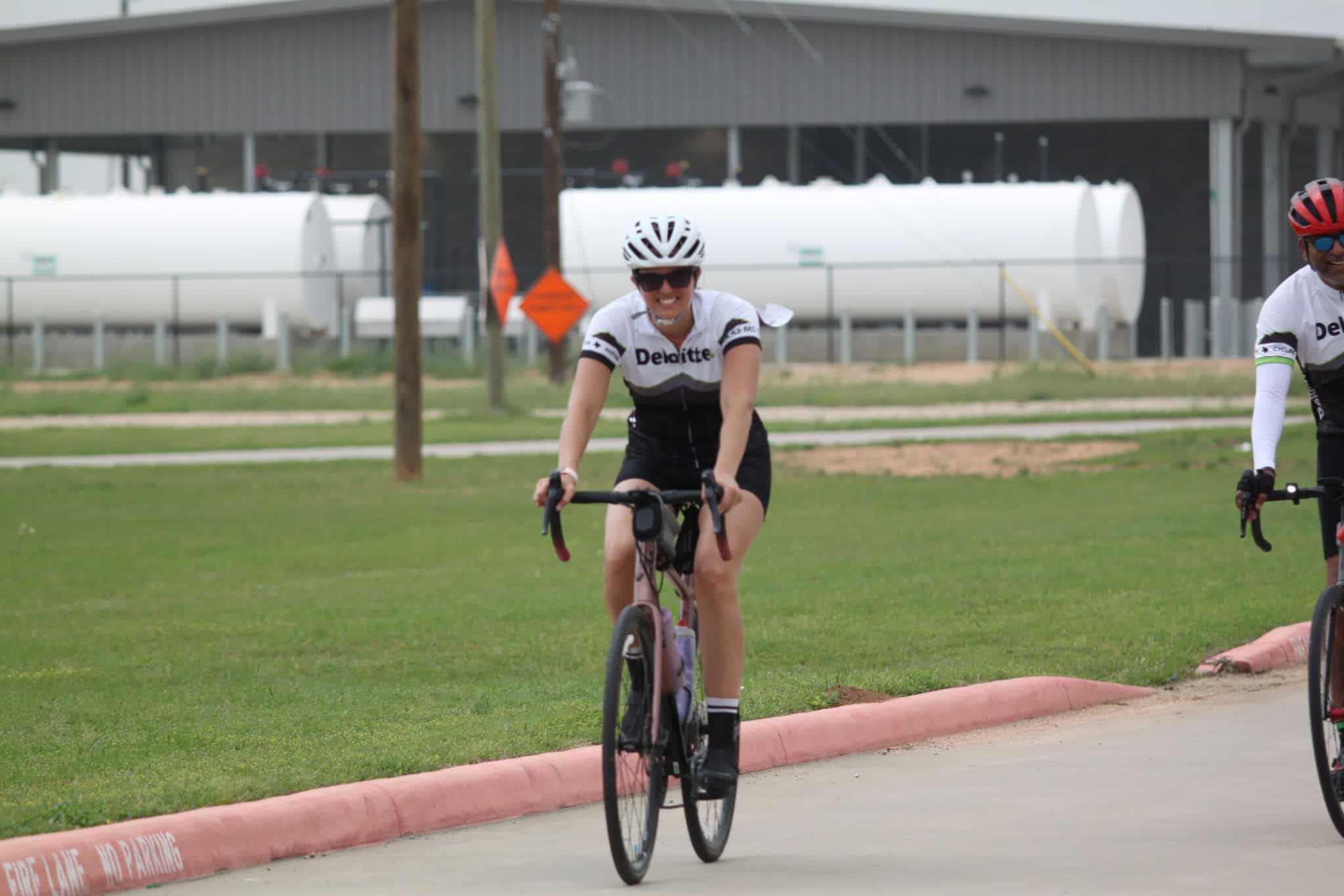 Bright female cyclist riding a bike outdoors in a casual athletic outfit, promoting Bluebonnet Express bike event.