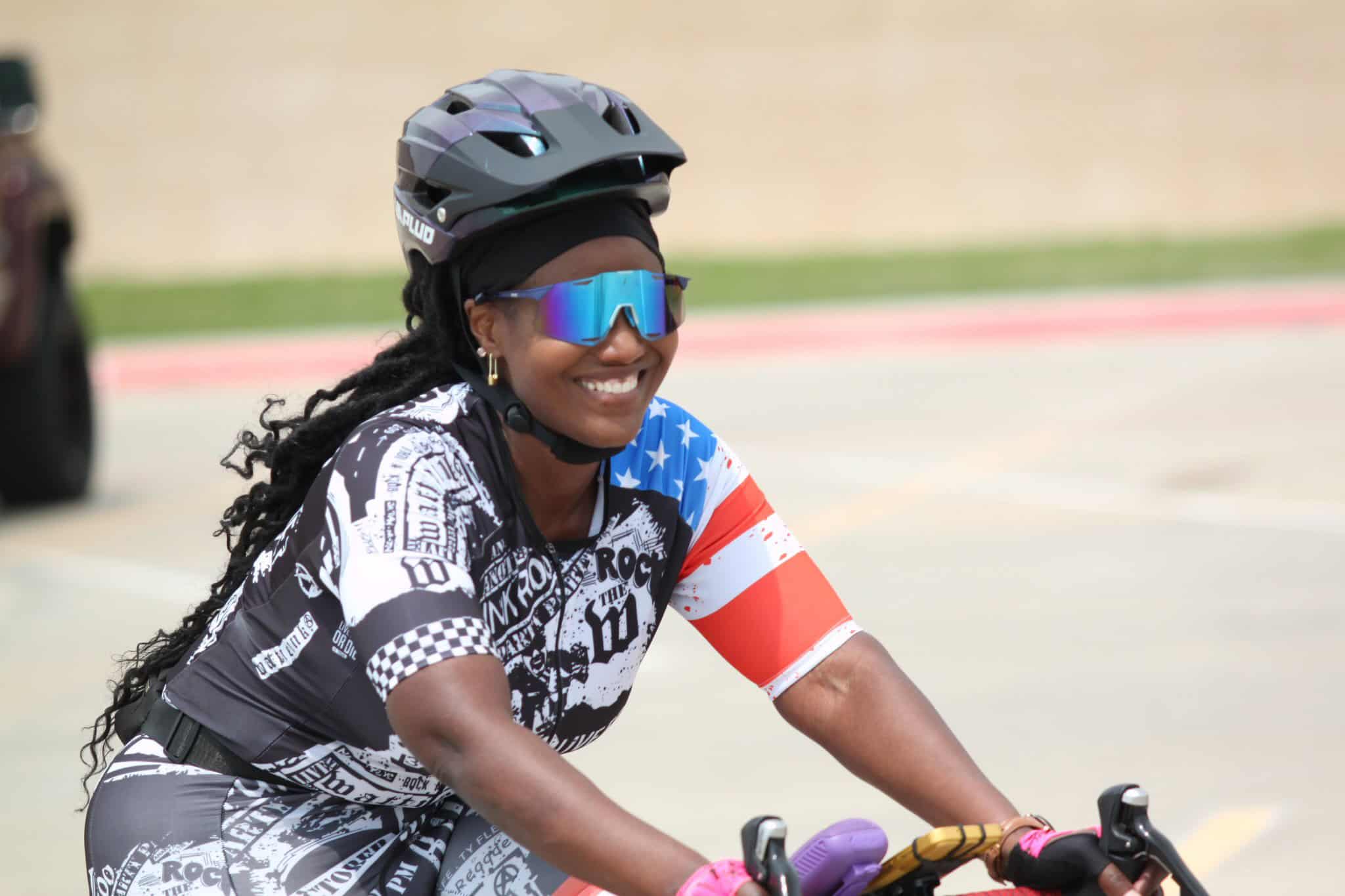 Bright smiling woman cyclist wearing helmet and sunglasses on a sunny day.