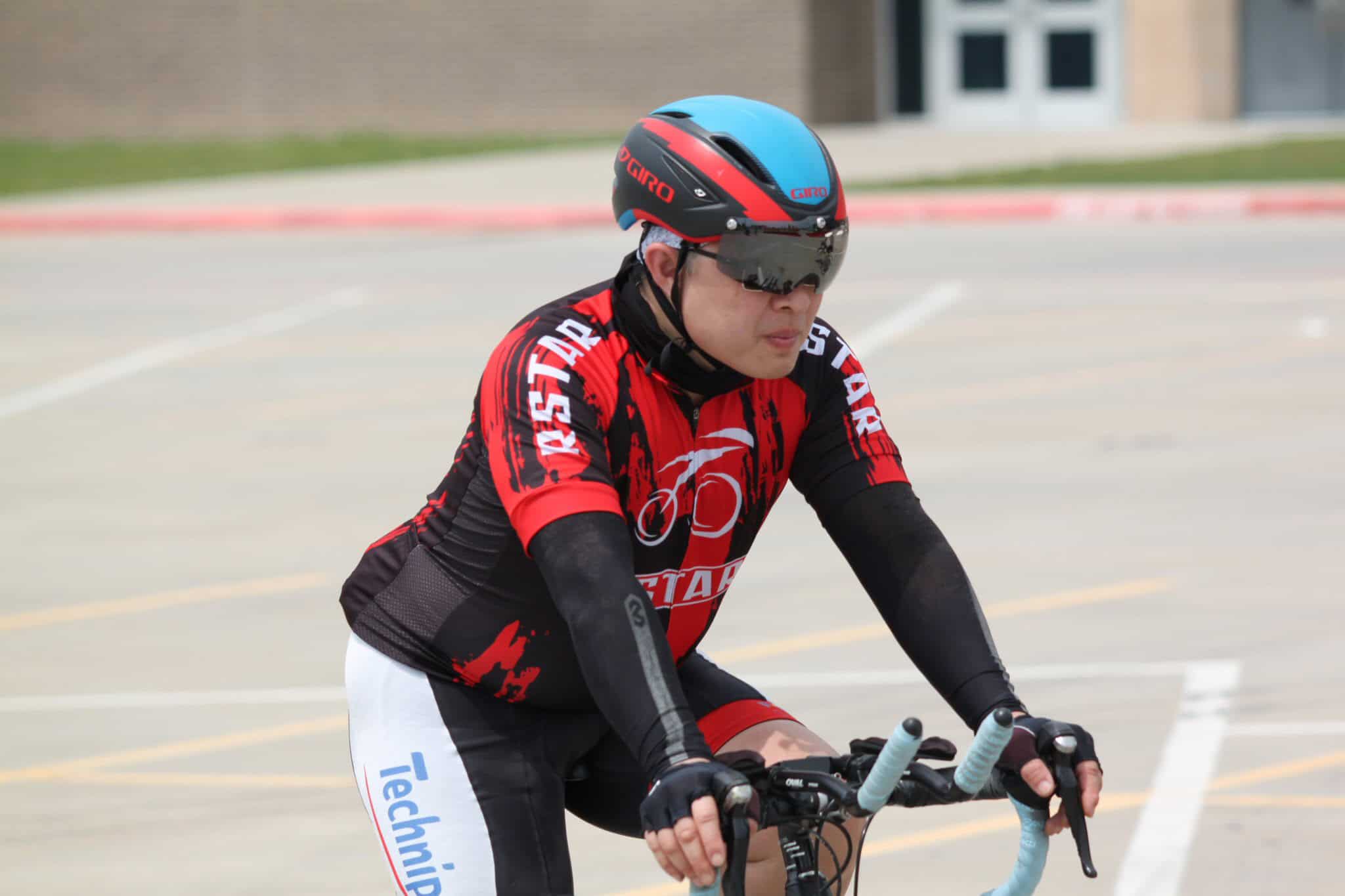 Rider wearing cycling gear, helmet, and sunglasses on a bicycle during outdoor ride for Bluebonnet Express.