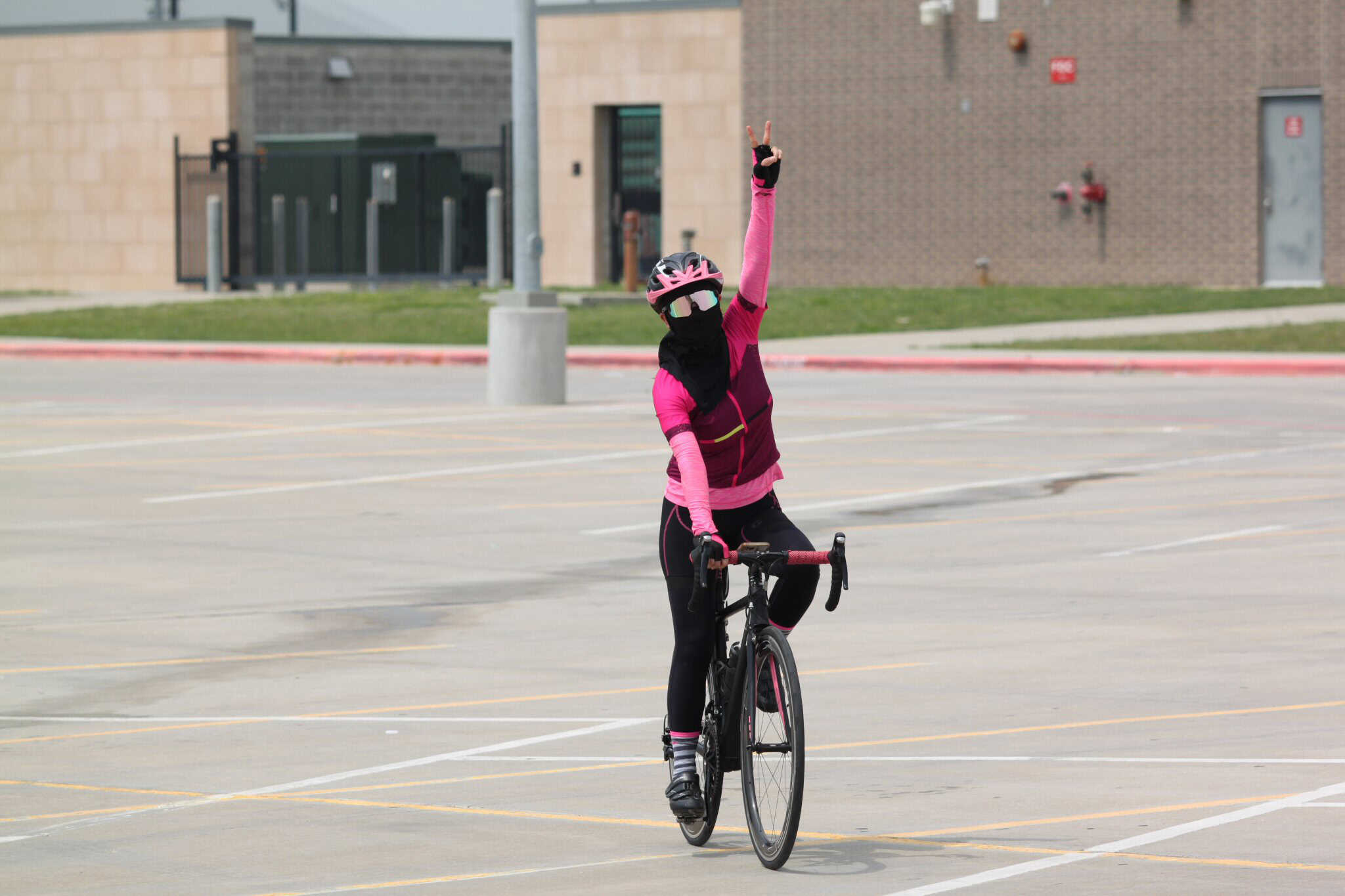 Viking-style cyclist on bike in a parking lot, wearing pink and black riding gear.