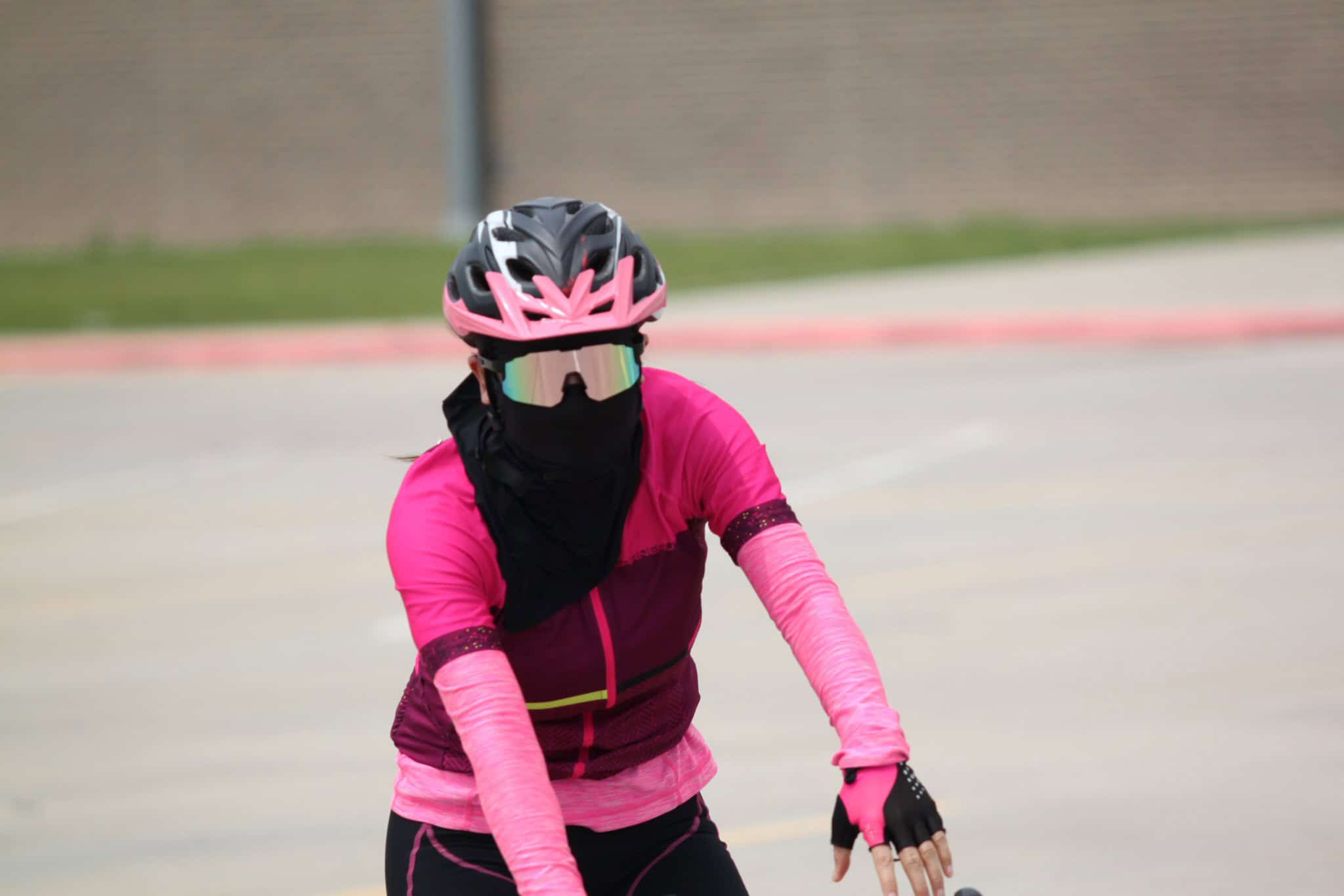 High-speed female cyclist wearing pink helmet and gear during cycling event.