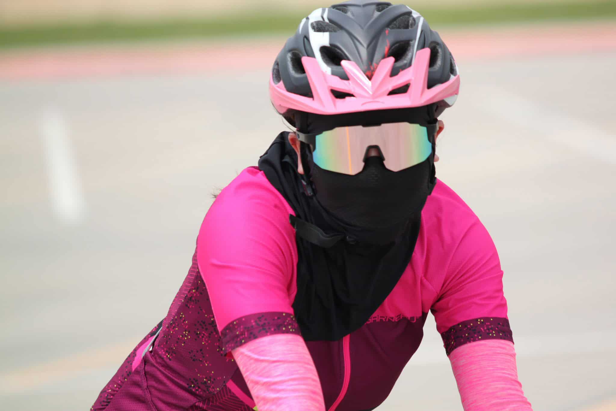 Bright pink cycling helmet and sunglasses worn by female cyclist during outdoor ride.