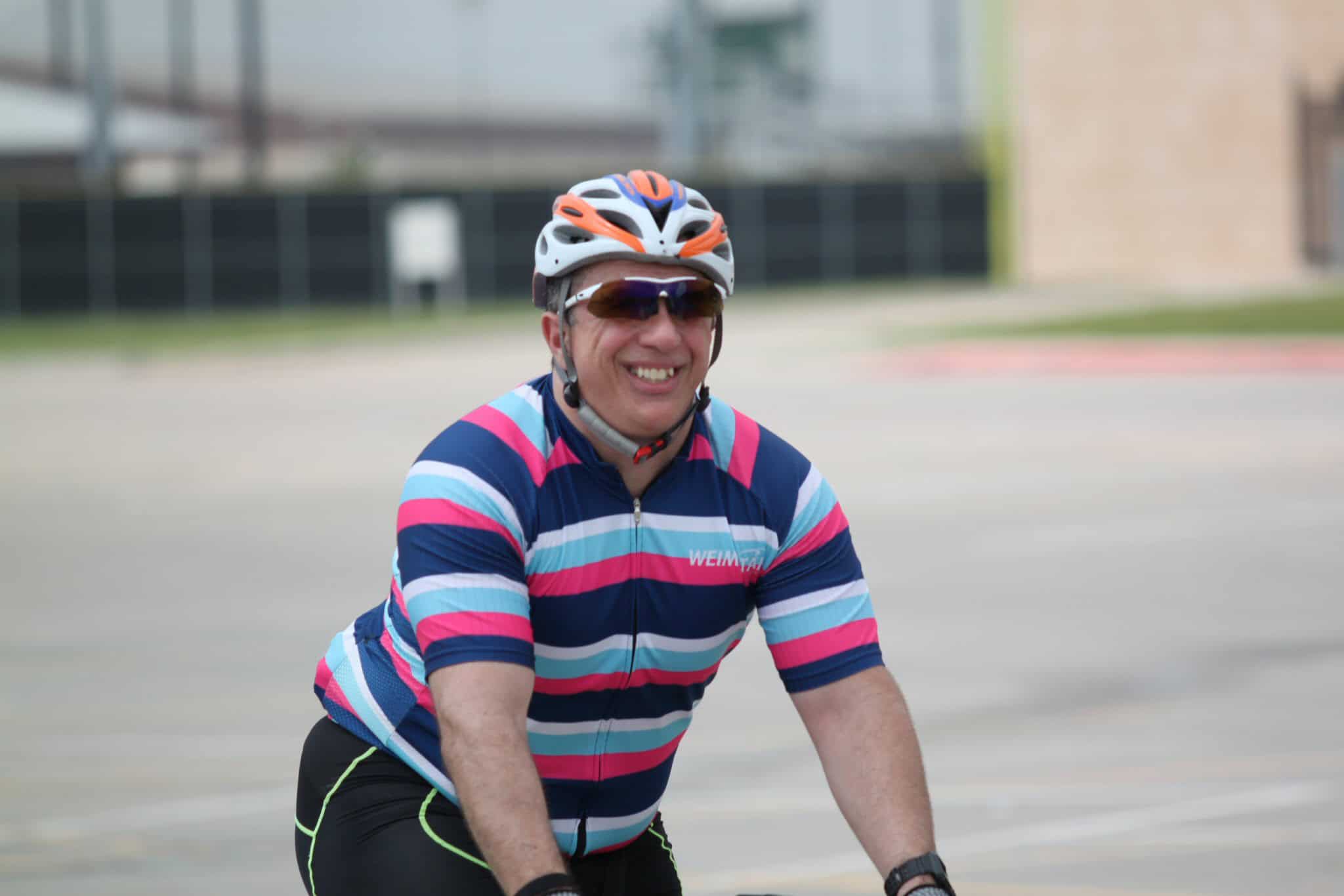 Brightly dressed cyclist with helmet and sunglasses enjoying a ride outdoors.