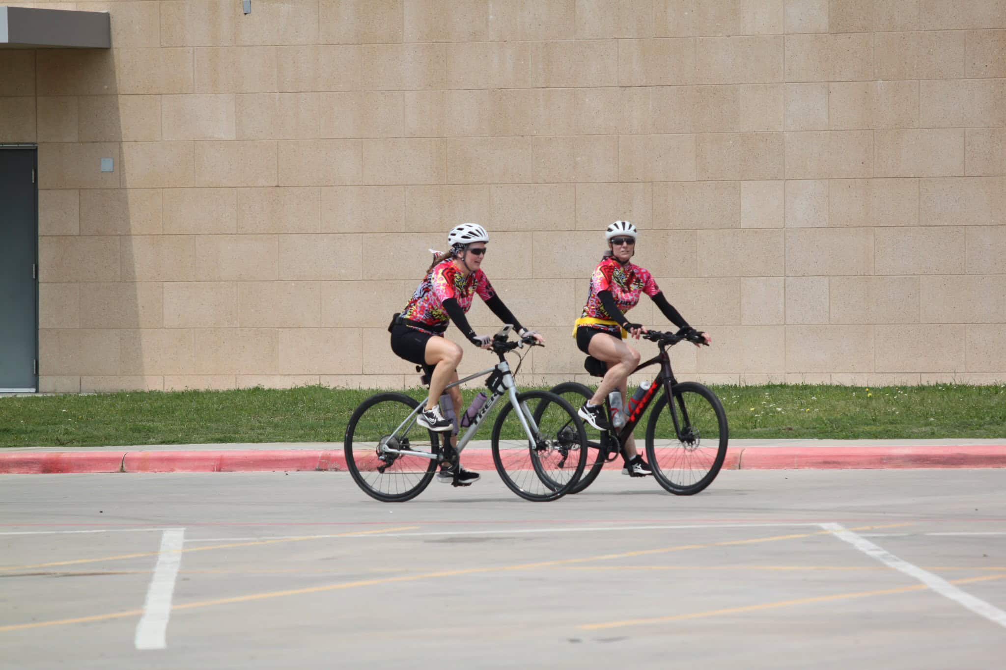 Women cycling on Bluebonnet Express route during daytime, wearing sports gear and helmets for outdoor bike ride.
