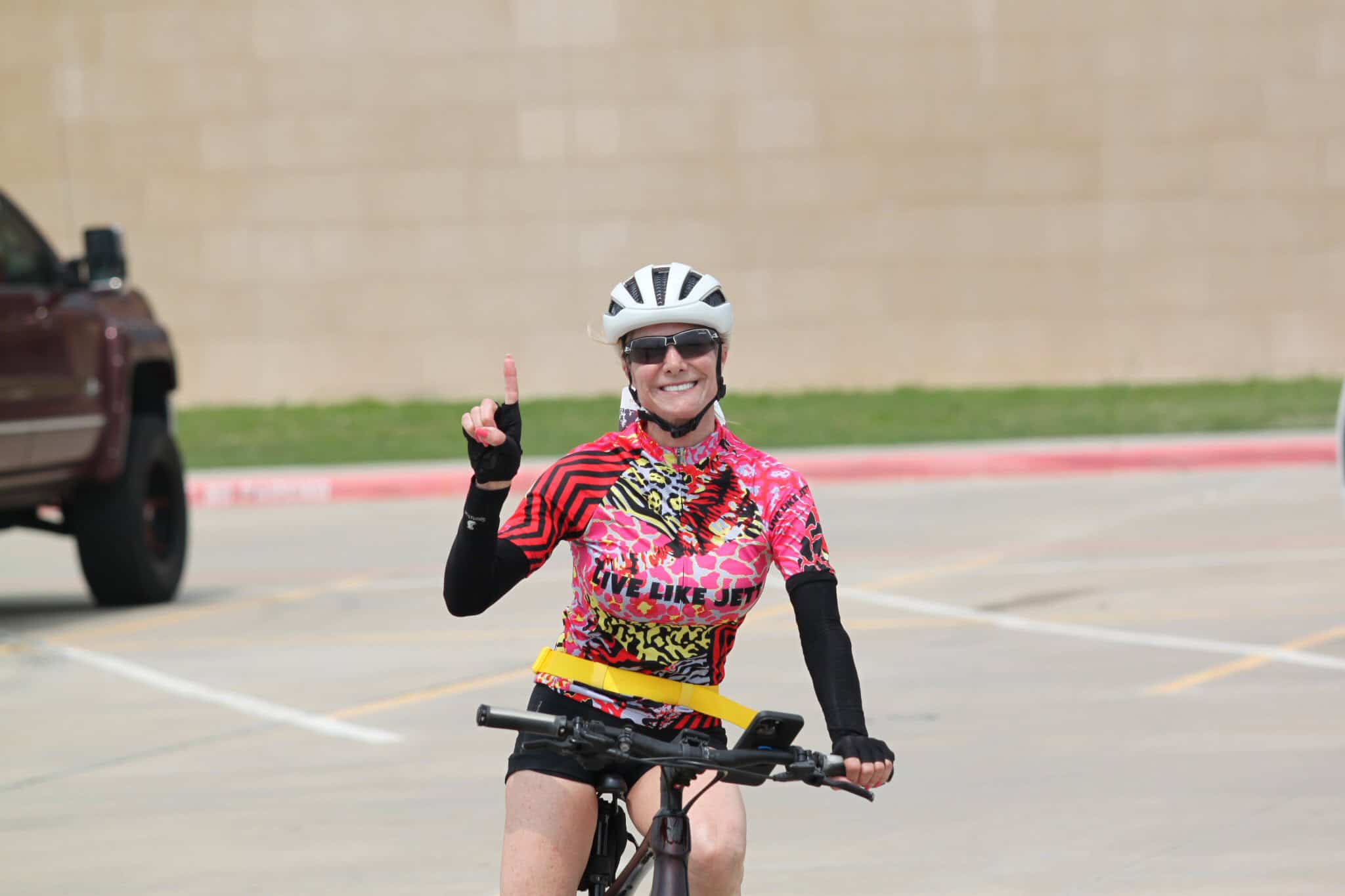 Smiling cyclist celebrating ride at Bluebonnet Express event, wearing colorful cycling gear and safety helmet.