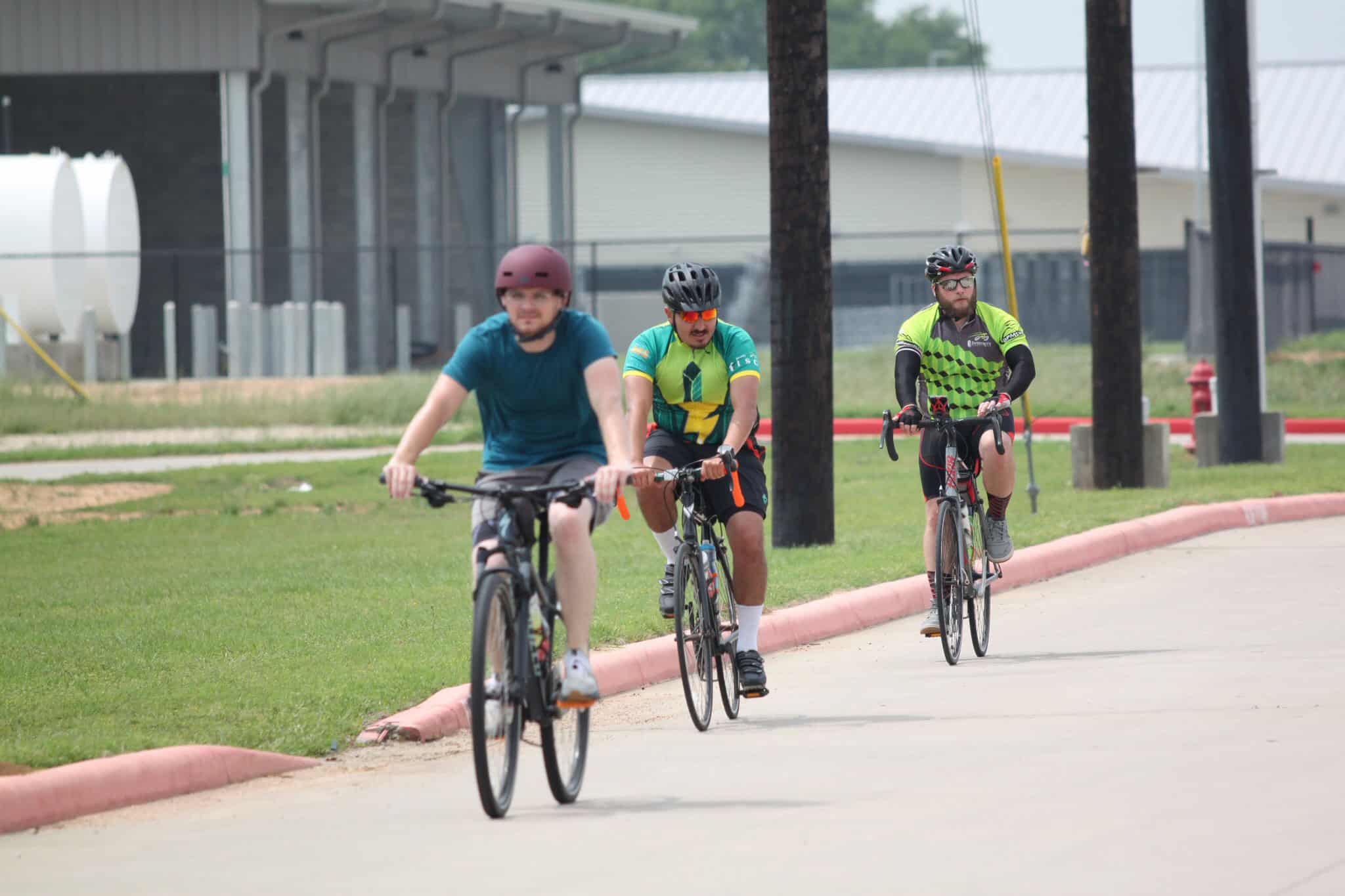 Bright outdoor bike ride with three cyclists on a paved path, showcasing Bluebonnet Express biking tour.