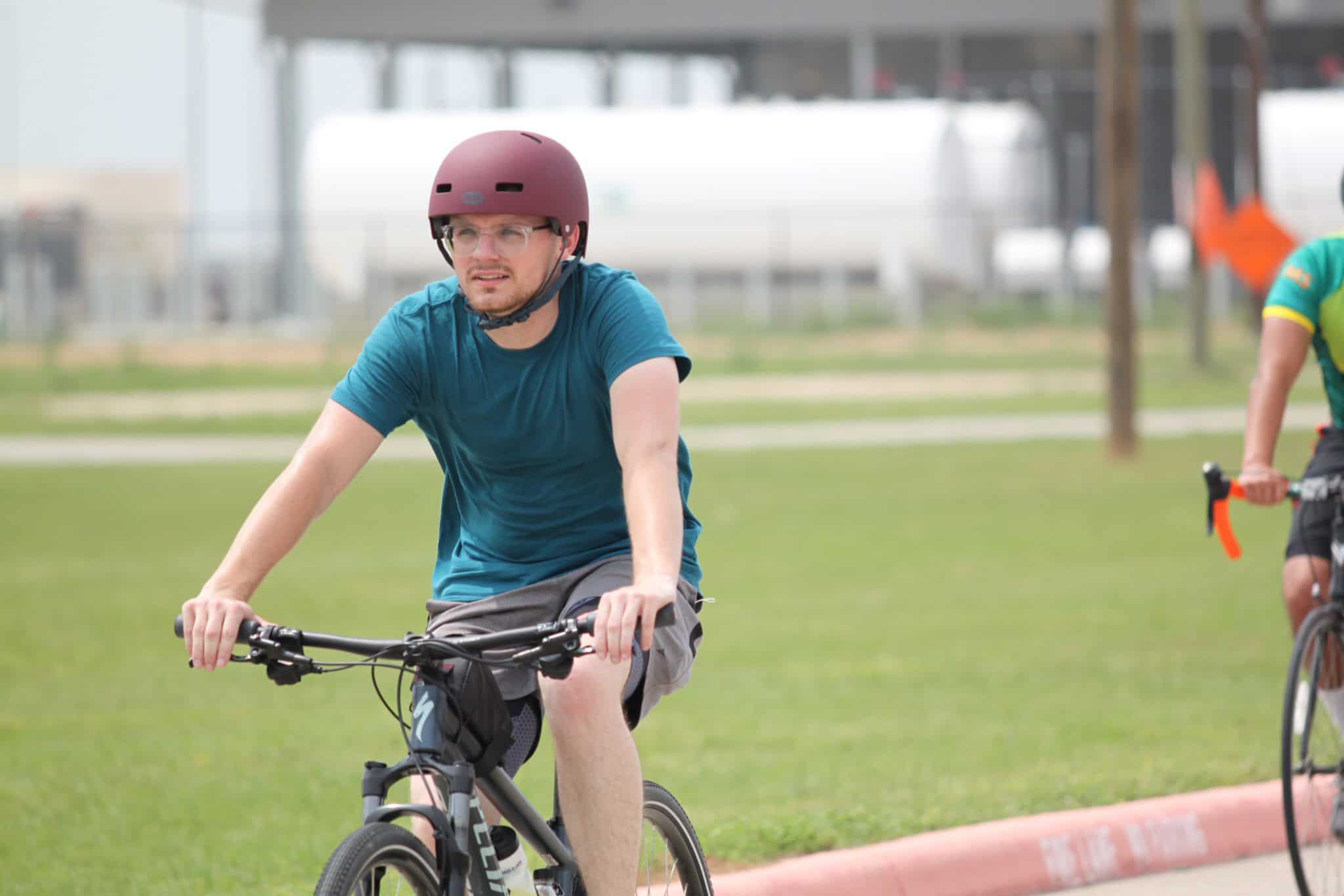 Young man riding bike in protective helmet at Bluebonnet Express, an outdoor cycling event.