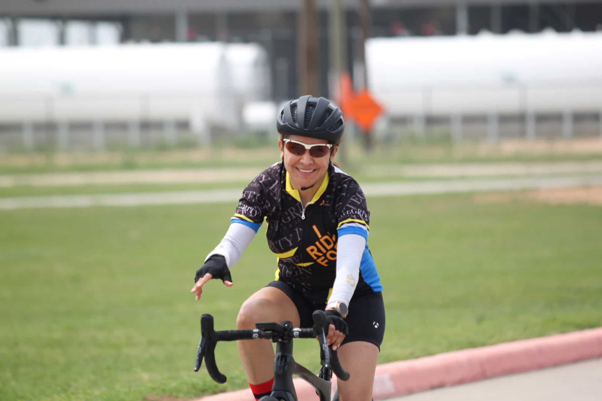 Active female cyclist smiling in riding gear, enjoying a bike ride outdoors.