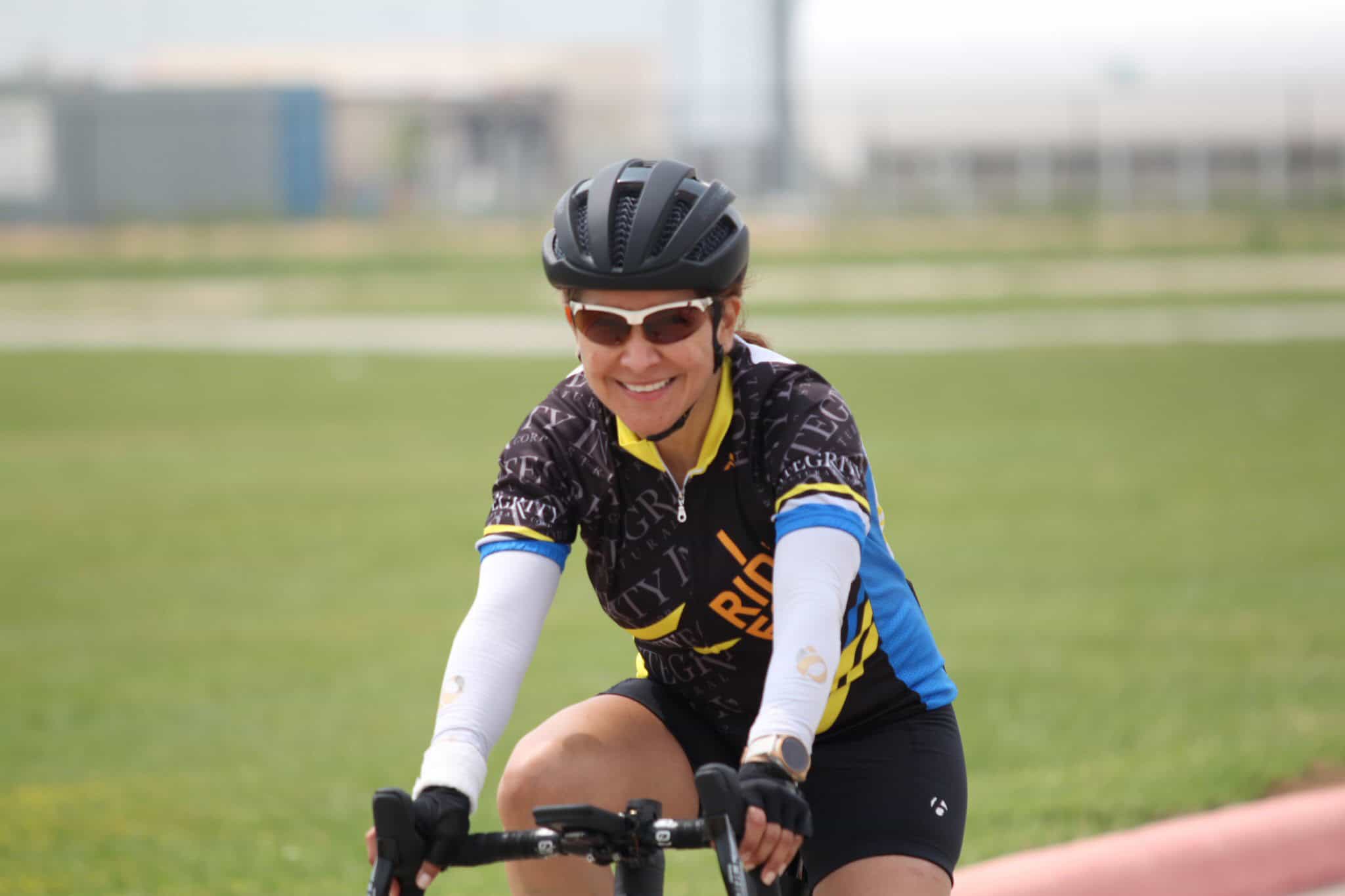 Vibrant female cyclist smiling during a ride on a sunny day, promoting Bluebonnet Express bike services.