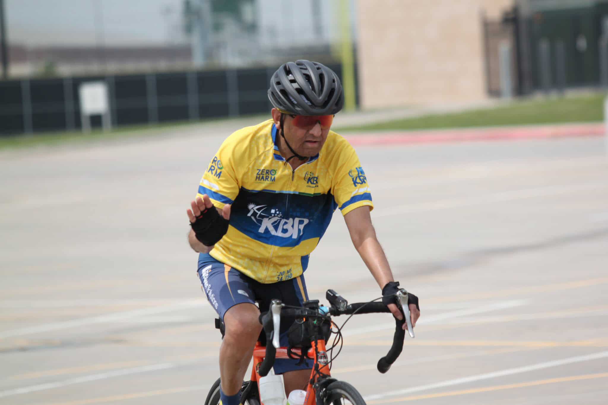 Bright yellow cycling jersey featuring KBR logo and eco-friendly slogans, worn by cyclist on a training ride.