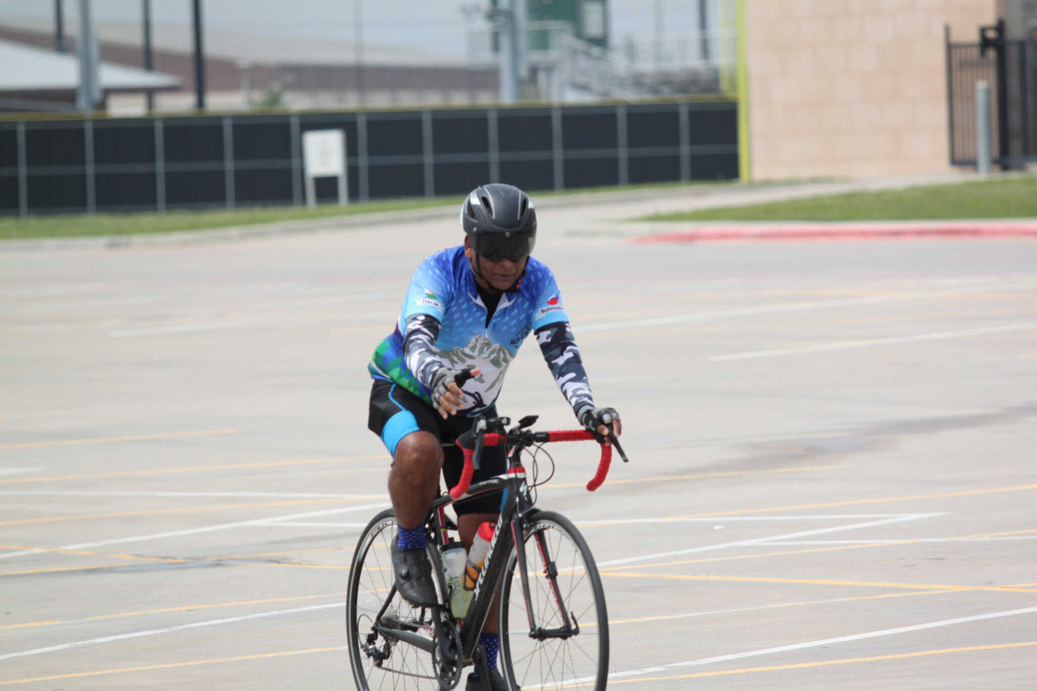 Energetic cyclist riding in a large, empty parking lot for Bluebonnet Express event.