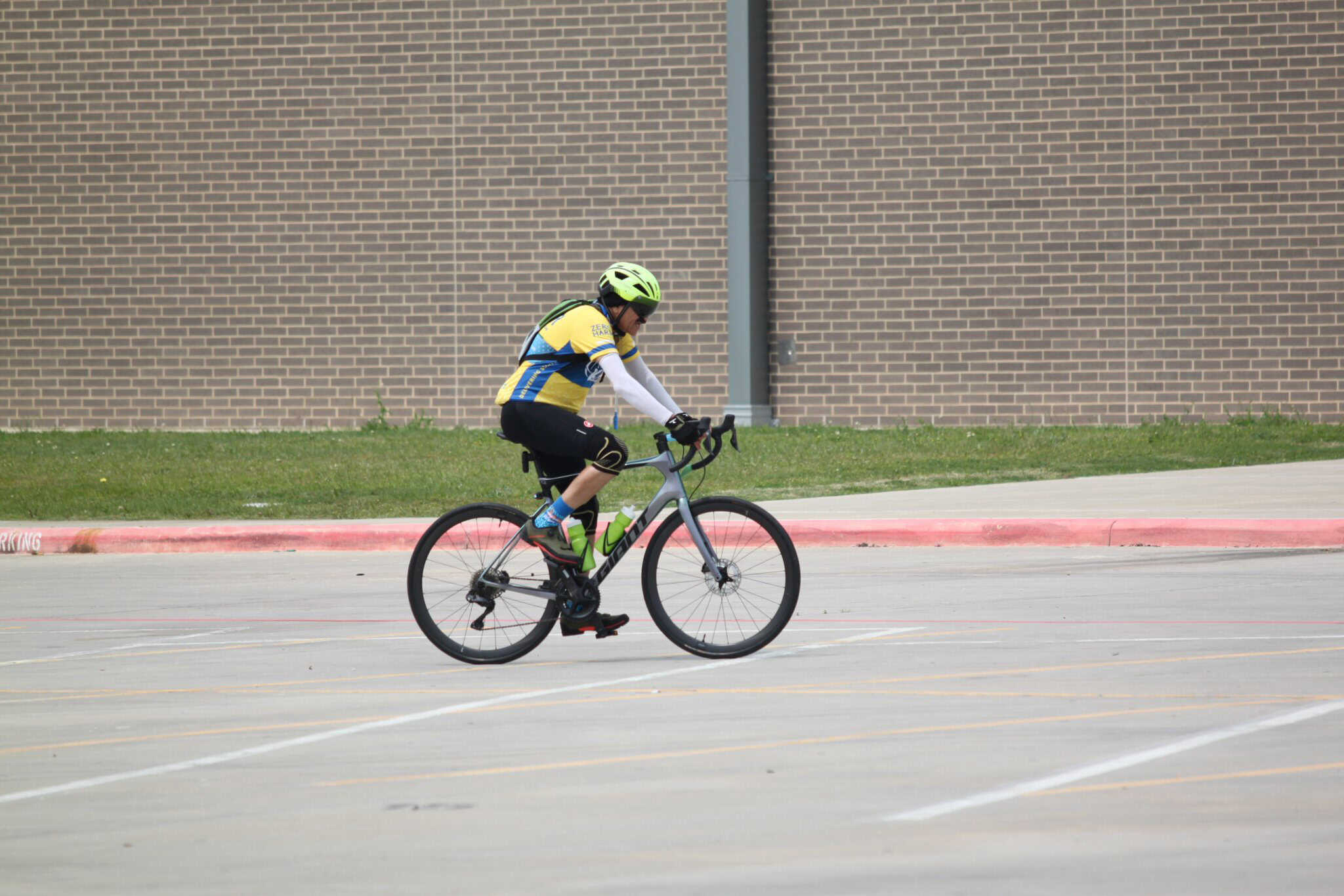 Bright cyclist riding a bike with safety gear in a parking lot for Bluebonnet Express.