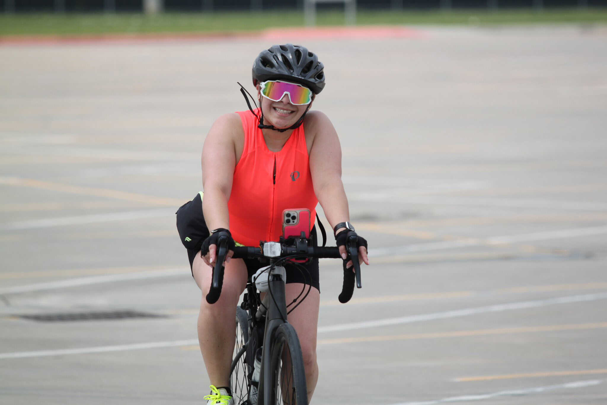 Bright smiling woman in sports gear riding a mountain bike on an empty parking lot.