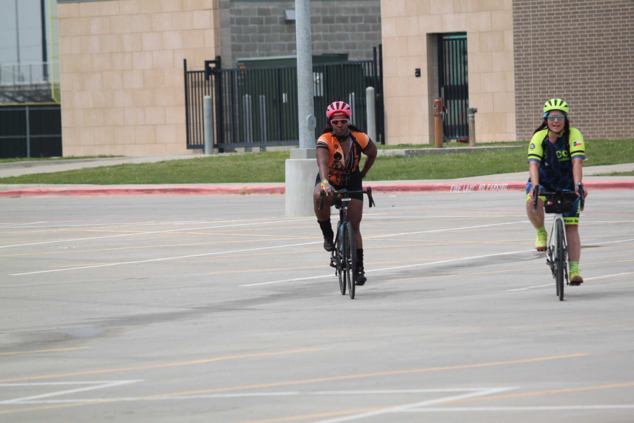 Brightly dressed cyclists riding on an empty parking lot, promoting outdoor biking with Bluebonnet Express.