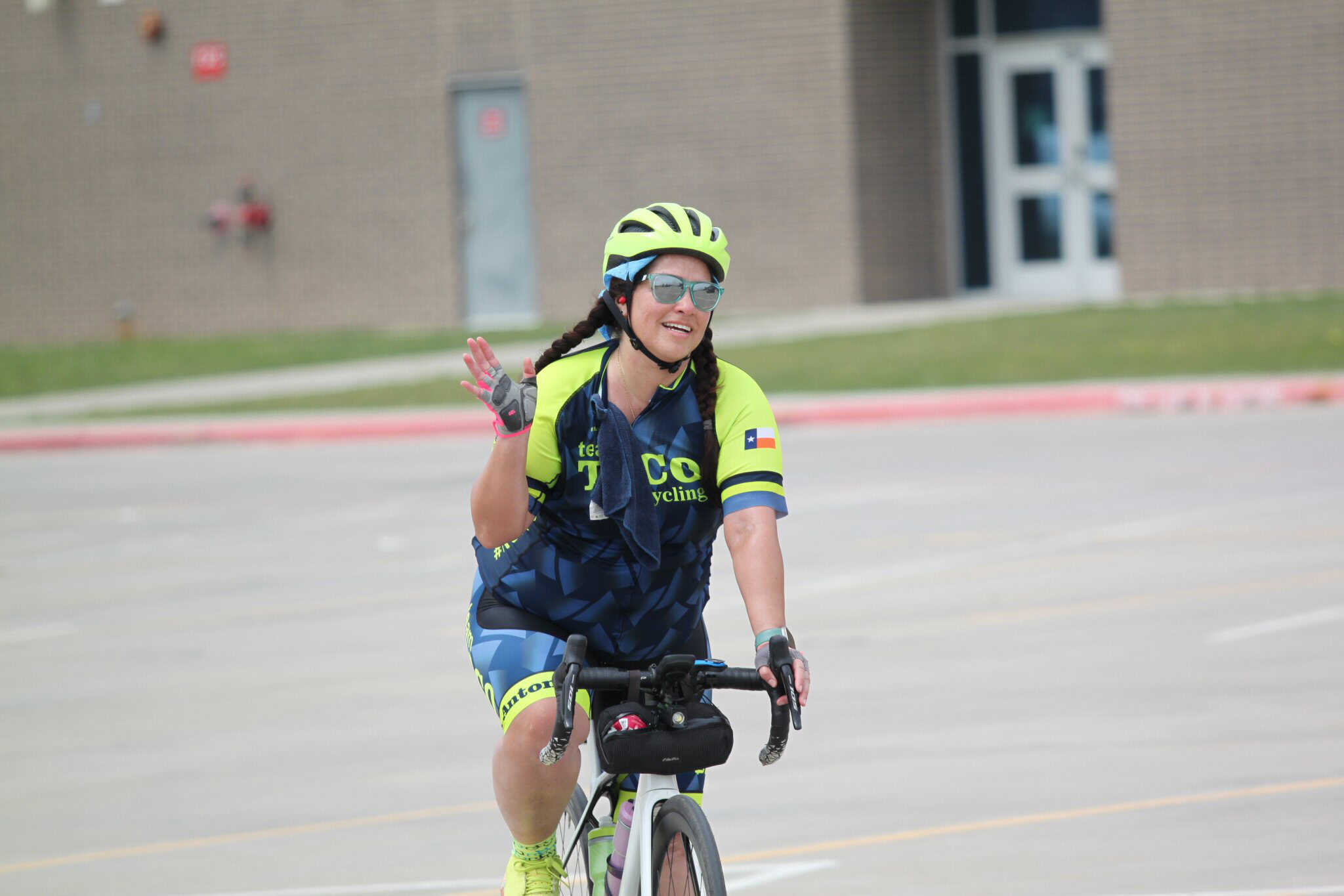 Bright female cyclist waving during Bluebonnet Express cycling event, showcasing Texas-themed cycling gear.